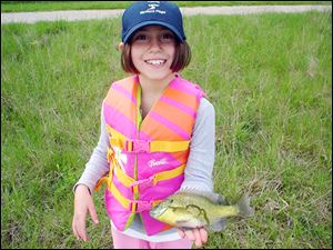 Lauren Drzewiecki, 8, above, wears an ear-to-ear smile as she proudly shows off a bluegill she caught while she and her sister, Samantha, 4, below, fished with their dad, Norman.
