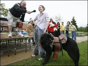 David E. Nixon, president of Monroe County Community College, interviews Brandy Werner, who entered her dog, Amos, a Newfoundland-St. Bernard mix, in the costume category at a recent dog show at the school. The event aimed to raise money for Project Second Chance, which gives children at the county youth center the chance to work and train dogs from the Monroe County Humane Society.