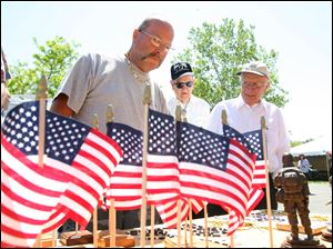 Marine Corps veteran Hal Bailey, left, who served in the Vietnam War, looks at statues and flags for sale at the Toledo Vet Center. Also examining the items yesterday were World War II veterans Martin Gerken, center, and Bob Scott. Mr. Gerken was a POW for 18 months in Germany during WW II, while Mr. Scott was a paratrooper. 