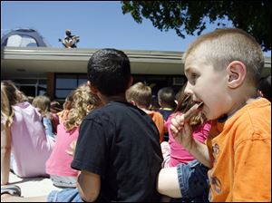 Zachary Miller, 5, eats an ice-cream treat while listening to the reading.
