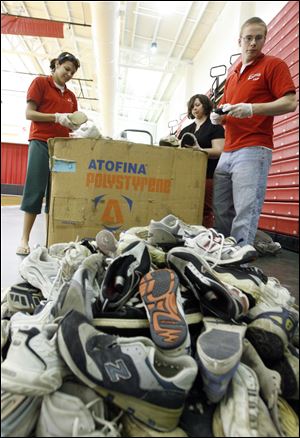 From leftto right: Sophomores Rachel Wismer, Molly Jordan, and Joel LaPoint of the Owens Community College Environmental Club sort through donated sneakers that will be shipped to the Nike Recycling Center in Wilsonville, Ore.