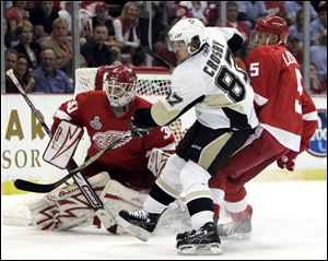 Nicklas Lidstrom, right, battles with the Penguins' Sidney Crosby in front of goalie Chris Osgood.