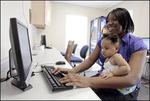 Raeshon Silver, who recently graduated from the Glass City Academy, works on a computer with duaghter Surrya Silver, 1.