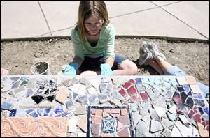 Rhys Niner puts on an adhesive for tiles that she will place on a permanent bench for the school grounds.