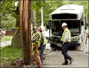 Toledo Edison workers prepare to replace an electric pole after it was hit by a TARTA bus, Wednesday.