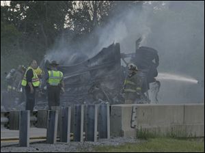 Safety officials surround the wreckage of a tractor-trailer
that crashed and burst into flames on the Ohio Turnpike near
Swanton. Westbound lanes were closed for about an hour after
Monday night s crash, which killed the driver. 