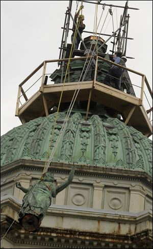 The statue of Lady Justice is hauled to the top of the courthouse dome, where workers from Midstate Construction wait to secure it in place. It has held its lofty perch atop the stately clock tower since 1899. 