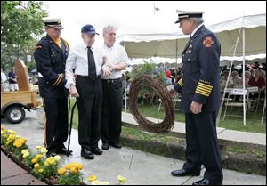 Toledo Fire Chief Michael Wolever waits with a wreath to be placed at the Firefighters Memorial in Chub DeWolfe Park by retired Deputy Chief Richard Hunt, assisted by his son Robert and fire Lt. Richard Knight, left. The elder Mr. Hunt, 92, is the department s second-oldest retiree. Yesterday s ceremony, marking the 48th anniversary of the Anthony Wayne Trail fire, was preceded by an awards ceremony. 