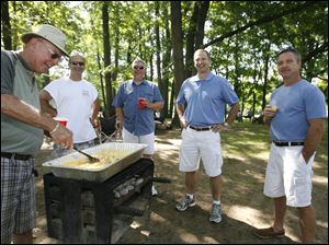 CTY dads22p    Jim Coyle, left, of Maumee, makes scrambled eggs and bacon at Wildwood Metropark in Toledo, Ohio on June 21, 2009 with family. From elder Coyle, left: son Jim Coyle, of Sylvania; son-in-law Paul Huguelet, of Oregon; son Mike Coyle, of Sylvania; and son-in-law Chris Rucki, of Oregon. The Coyles have been celebrating father's Day together at Wildwood for several years. Dads and friends on Father's Day in Toledo, Ohio on June 21, 2009. The Blade/Jetta Fraser