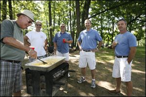 CTY dads22p    Jim Coyle, left, of Maumee, makes scrambled eggs and bacon at Wildwood Metropark in Toledo, Ohio on June 21, 2009 with family. From elder Coyle, left: son Jim Coyle, of Sylvania; son-in-law Paul Huguelet, of Oregon; son Mike Coyle, of Sylvania; and son-in-law Chris Rucki, of Oregon. The Coyles have been celebrating father's Day together at Wildwood for several years. Dads and friends on Father's Day in Toledo, Ohio on June 21, 2009. The Blade/Jetta Fraser