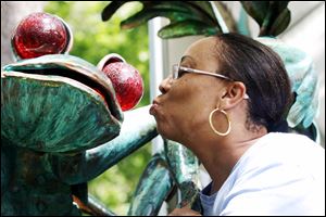 Zina Mason of Findlay might be thinking prince as she pretends to kiss a frog at the Crosby Festival of the Arts. Garden art bloomed thoughout the grounds.