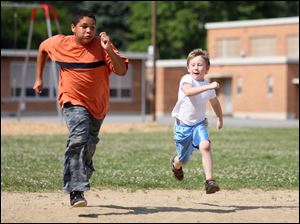 Slug: ROV ballwithmom                 Date 6/27/2009           The Blade/ Amy E. Voigt              Location: Toledo, Ohio  CAPTION:  Justin Krieg (cq), right, and Andrew Malone, left, from Toledo, race on the diamond at Monac Elementary School on June 27, 2009.