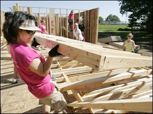 Above, Michelle Thompson of the Cass Road Baptist Church in Maumee helps erect a wall as the Maumee Valley Habitat for Humanity builds a five-bedroom ranch house on Ansonia Street in Oregon. The project is to be finished this month.  Five area churches are helping to complete the task. Below and bottom: Vickie Shutters of Swanton and Bill Forsee of Christ Presbyterian Church in Toledo join the group.
