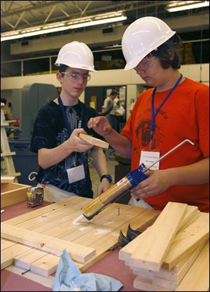 Clarence McCune, 14, left, and Ben Diehl, also 14, glue a cross-piece for the chair they are making at the camp.