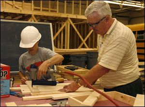 Justin Sauppe, 14, uses a nail gun and Bob Johnson holds the spacing as together they assemble a chair during last week's Construction Fun Camp at Sylvania Southview High School. 