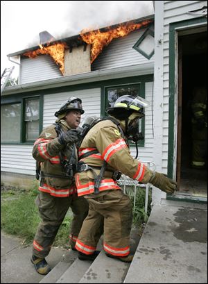 Sylvania Township firefighter Greg 'Jumbo' Wilcox, left, guides trustee Carol Contrada into the 'controlled-burn house.' Ms. Contrada had participated in exercises before, but this was her first experience with flames.
