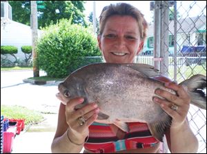 Nicole Jiminez shows off the 18 -inch, 4-pound pacu she took from Maumee Bay off Edgewater Drive in Point Place.