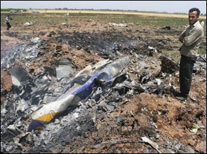 In this photo released by the semi-official Iranian Students News Agency, an unidentified man observes the scene of a plane crash near the village of Jannatabad, outside the city of Qazvin, around 75 miles northwest of Tehran in Iran on Wednesday.