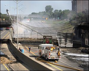 Crews remove debris from the collapsed section of bridge over northbound I-75 north of Detroit, where a fuel tanker exploded and an overpass collapsed Wednesday night. Workers also started demolition yesterday of the weakened but still standing span over the southbound lanes. The accident occurred when a car spun out of control along a winding section of the highway and caused the tanker to crash. Investigators with Hazel Park, a Detroit suburb where the accident occurred, said the drivers of the car, the tanker, and a third tractor-trailer in the crash escaped with only minor injuries. 