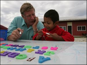 Ken Green works on language fundamentals with Gustavo Ramirez, 3, at a migrant camp in Woodville, Ohio. The boy is part of the Woodmore district's summer education program for migrants.