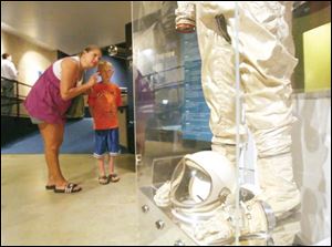 Dawn Luthman of Russia, Ohio, teaches her son, Dawson, 7, about Neil Armstrong s space suit at the Armstrong Air & Space Museum.