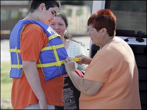 CTY boatride21p  07/20/09  The Blade/Dave Zapotosky Caption: Todd Harrison, 11, of Toledo, gets fitted for a life jacket by Pamela Proudfoot, right, before taking  a boat ride on the Maumee River, in Toledo, Ohio, Monday, July 20 2009.  Looking on is Ruth Esparza, center, Todd's mother. The ride was the fourth of sixth for special needs children put on by Safe Kids Greater Toledo, this summer.  The rides are free to special needs children and a caregiver.  (Call or email Pamela Proudfoot, coordinator of community outreach for Toledo Children's Hospital to register. 419.291.8487 or pamela.proudfoot@promedica.org.  There are two more boat rides in August) Summary: Safe Kids Greater Toledo (lead agency: Toledo Children's Hospital)is hosting a series of one-hour boat rides for children with special needs. The children and their caregivers will learn about water  safety and experience a one-hour boat tour of the Toledo Port. The program is supported by a grant from the Ohio Department of Natural Resources Division of Watercraft.