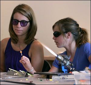 Melissa Hansen and her daughter Hannah, 11, of Curtice learn to make glass beads. Visitors could also make glass magnets, craft a chandelier, and watch glass-blowing demonstrations.