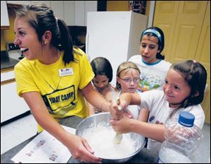 Laura Rodriguez, left, assistant director, helps Madelyn Jeffrey,7, Ally Devries, Ashley Moylan, 13, and Gabrielle Whitzel, 6, mix pancake batter.