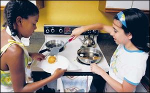 Sierra Strong holds the plate while Ashley Moylan removes pancakes from the pan.