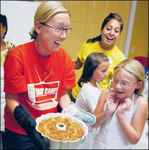 Ally Devries, 8, is excited when Culinary Camp instructor Amy Tanner takes the monkey bread the campers made from the oven.