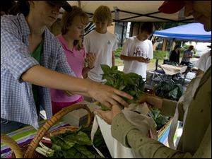 Olivia Degitz, 15, left, hands fresh basil to a customer at the Metro Early College High School in Columbus. The students, who use a plot of land owned by Ohio State University, also run a farm market.