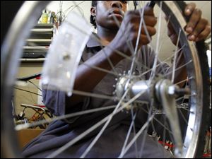 Volunteer William Rowlett removes a tire from a rim to be repaired.