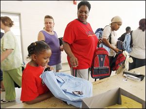 Slug: REL BACKPACKS20p          Date 8/20/2009           The Blade/ Amy E. Voigt           Location: Toledo, Ohio  CAPTION:  Kennedy Gibson-Harrison, left, reacts to her new backpack and school supplies while her mother Shelly Taylor (cq), rightfrom Toledo, ushers her through the line at The Salvation Army on August 20, 2009.