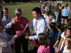 From left: Julie Everly, co-principal of Hollywood Elementary in Monroe, superintendent David Taylor, school board president Robert Yeo, and co-principal Ryan Starr take part in a knot tying that symbolically connects Cantrick and Hollywood schools. Ribbon was stretched from the front doors of each school to symbolize the unity of the two schools. 