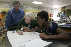 Marty Perlak watches the work of Carlie Willis, a freshman, and Bre'shantis Saka, a sophomore, students in his biology class.