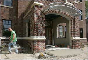 Dave Lindhurst, a worker with Bureau Concrete of Perrysburg, builds a concrete walk in front of the new entrance to the administrative offices of the Perrysburg School District. The trim is reminiscent of the  building that was erected  in 1931.