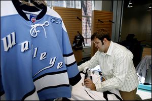 Slug: CTY arena01p Date:  09302009        The Blade/Andy Morrison       Location: Toledo       Caption: Tim Rupp, an employee of the Toledo Walleye, puts away merchandise at one of the shops at the Lucas County Arena, Wednesday, 09302009. Summary: