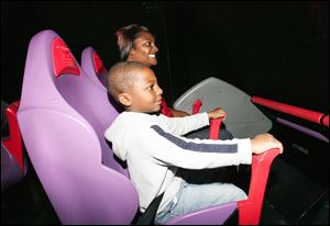 Sheneique McElrath of Toledo and her son Torrin Tyree, 5, hold on as a simulator at the Imagination Station helps them experience how it feels to drive a race car.