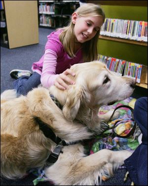Madeline Potts of Rossford pets Finnie during the Read to the Dogs: Paws with a Heart program at Rossford Public Library.
