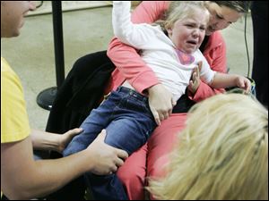 Matt Frey of Bowling Green and his wife, Jaimee, try to hold their daughter, Adrienne, 3, still so she can get a seasonal flu shot during a clinic administered by the Wood County Health Department. Adrienne was not exactly happy about getting a shot, even after watching her mom get one during the daylong clinic, held at the Wood County Fairgrounds in Bowling Green.