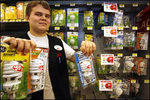 Matt Murnen, a marketing student at the University of Toledo who works at Werkman's Ace Hardware, holds energy-efficient bulbs like the ones FirstEnergy wants to distribute for $10.80 each. 