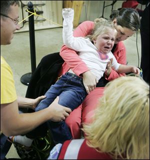 Matt Frey of Bowling Green and his wife, Jaimee, try to hold their daughter, Adrienne, 3, still so she can get a seasonal flu shot during a clinic administered by the Wood County Health Department. Adrienne was not exactly happy about getting a shot, even after watching her mom get one during the daylong clinic, held at the Wood County Fairgrounds in Bowling Green.