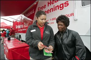 Technician Jamielah Mottley, left, consults with Gloria Wright of Toledo on the results of tests Ms. Wright underwent when the Walgreen health-screening bus was at the Monroe Street store.
