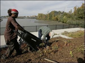 Toledoan Robert McCreary, 18, left, and Charlie Johnson mulch property at the Municipal Skyway Marina as part of a job-training program through Toledo Grows-CITE. Mr. Johnson is the CITE program manager on the job.