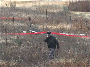 A police officer walks past wreckage of the plane that crashed in Raisin Township, Michigan. The
plane was en route Friday from Scranton, Pa., to the Lenawee County Airport near Adrian.