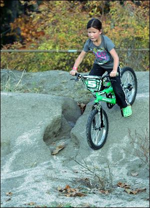 Self-professed tomboy Bianca Metreger, 6, is fearless as she bicycles down a dirt mound behind Maumee High School. She was playing yesterday with a friend, Deven Williams, also 6.