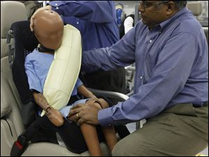 Ford technicians adjust a crash dummy with an inflatable seat belt on a demonstrator at Ford Motor Co. in Dearborn, Mich.