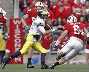 Tate Forcier attempts to get by Wisconsin's Blake Sorenson (9) as J.J. Watt closes in on the Wolverines' quarterback.