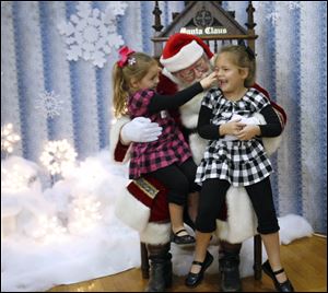 Slug:  CTY makeawish16p                              Date 11/15/2009           The Blade/ Amy E. Voigt                   Location:  Holland, Ohio  CAPTION:   Abigail Heywood (cq e not a), left and her sister Samantha Heywood, right, from Maumee, joke around while sitting on Santa's lap (Frank Alcorn) during the annual holiday party for the Make-A-Wish Foundation at Springfield High School on November 15, 2009. The event brought together over 450 Make-A-Wish children and family members (including 112 Wish Children) from throughout the 21-county area of Northwest Ohio to celebrate the holiday season.