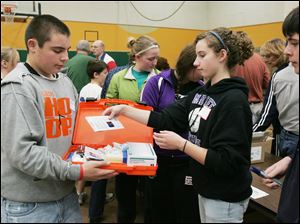 CTY kits23p  11/22/2009    Blade Photo/Lori King  Eddie Mader, 14, goes through the line to help make 200 volunteer caregiver kits at St. Joseph Catholic Parish Community Center Gymnasium in Maumee, OH. Putting an item in his hard kit is Jessica Buehler, 14.